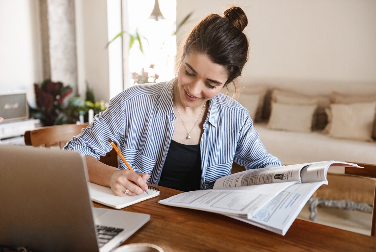 Mulher estudando com livros, notebook e caderno, seguindo um cronograma de estudos | Crédito: Divulgação