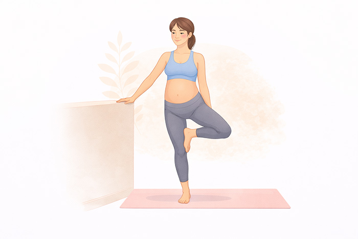 Mulher grávida praticando Vriksasana com apoio na parede para equilíbrio na postura da árvore. 