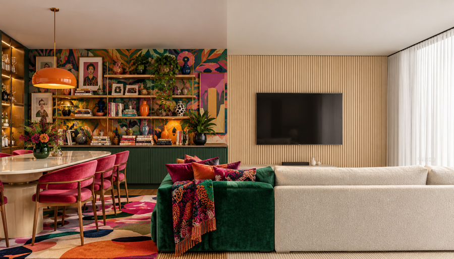 Sala dividia ao meio com o lado esquerdo decorado de forma maximalista, com cores, estampas e quadros, e o lado direito minimalista, com cores neutras e sem elementos chamativos de decoração.