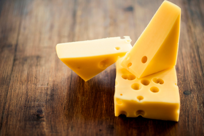 Pedaços de queijo Emmental com buracos característicos, ideal para combinações com vinho branco ou rosé. 