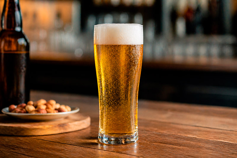 Copo lager/pilsner alto e fino com cerveja clara, ideal para preservar carbonatação 