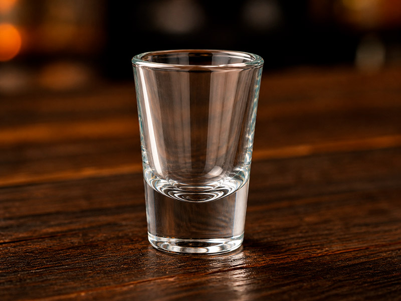Copo shot pequeno com base reforçada, usado para doses rápidas de destilados 