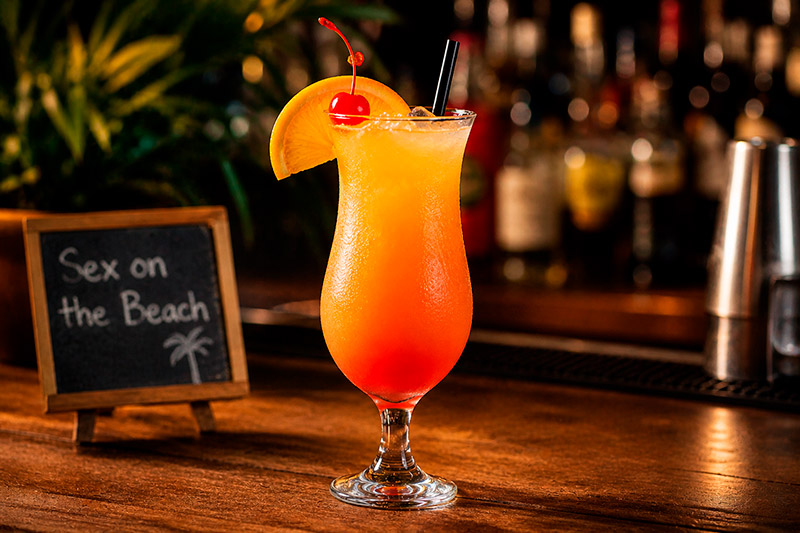 Taça hurricane com formato curvado servindo coquetel tropical, usada para drinks como sex on the beach 