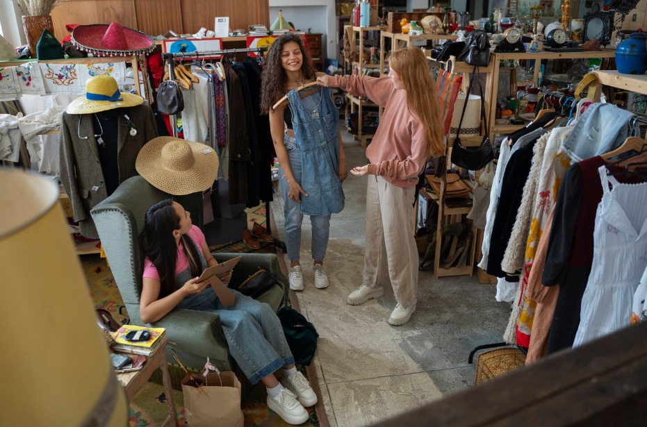 Meninas se divertem enquanto escolhem roupas para consumo consciente | Crédito: Freepik