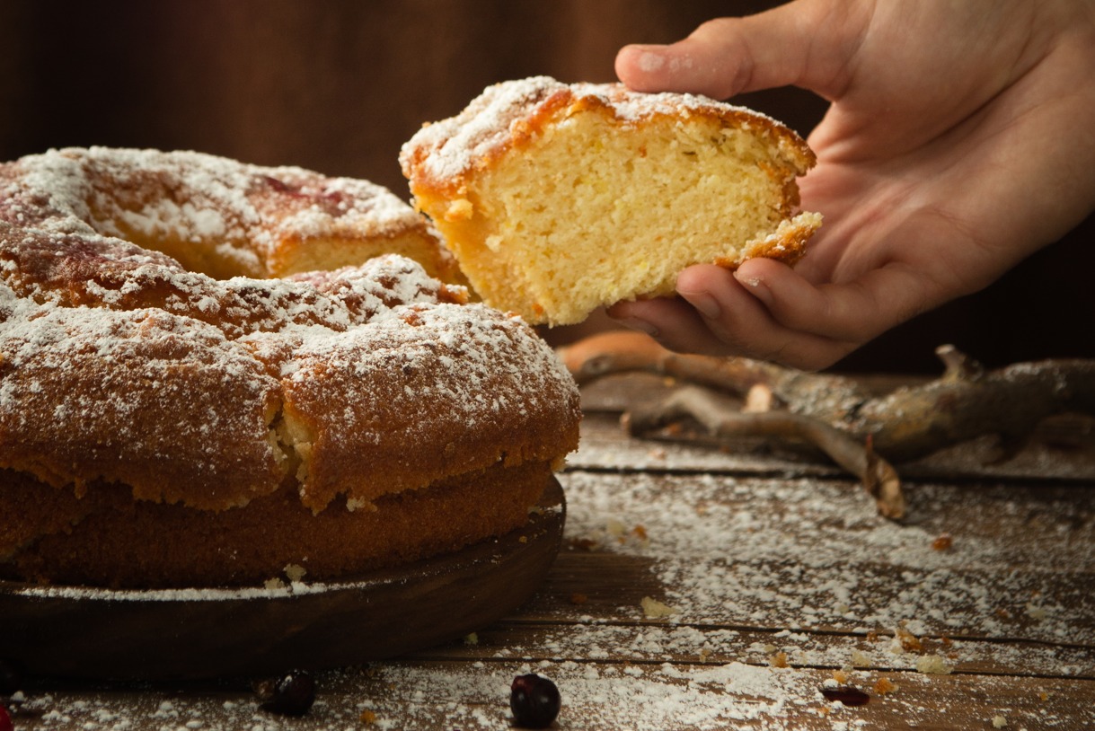 Predaço de um bolo macio sendo tirado por uma mão.